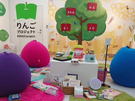 りんごプロジェクトの展示会場の様子。アクセシブルな本や資料、りんごをモチーフにした装飾が並んでいる