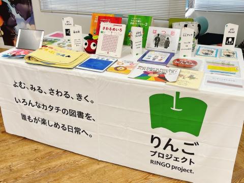 「よむ・みる・さわる・きく。いろんなカタチの図書を、誰もが楽しめる日常へ」と書かれたテーブルクロスの上にさまざまなアクセシブルな図書が並んでいる。